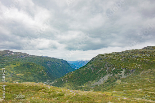 Norwegian summer landscape. Green and grey rocky mountains, mossy stones, cloudy sky