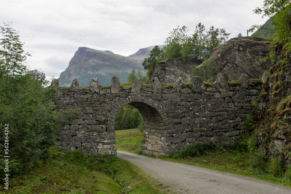 old stone bridge in Norway, near Geiranger. Misty mountains and cloudy sky on the background