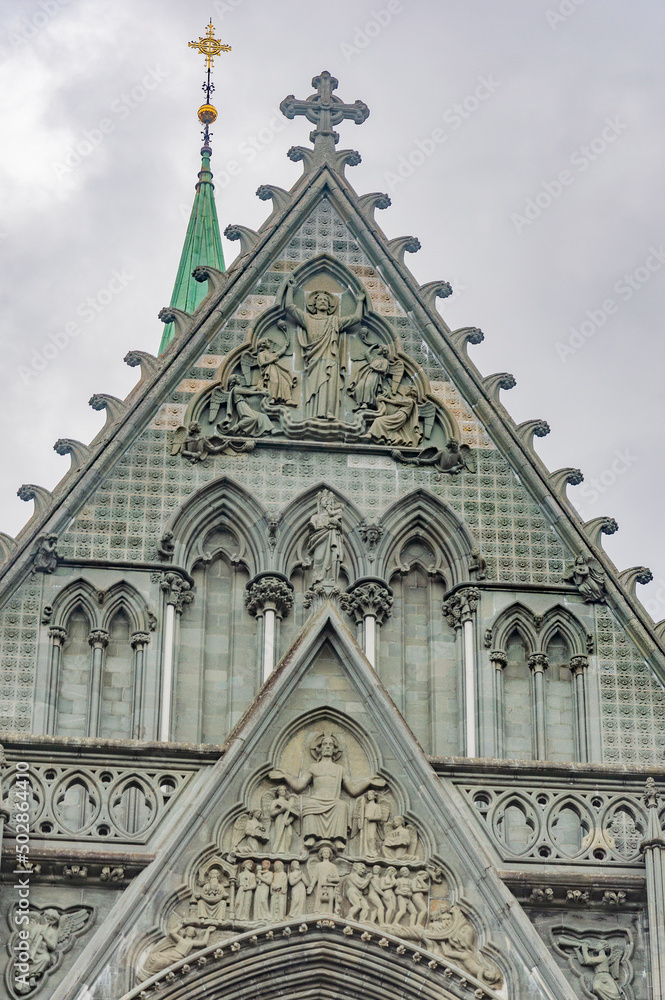 Fototapeta premium Nidarosdomen gothic cathedral in Trondheim, Norway. lilac sky with grey clouds, grey medieval stone walls and bell towers, figures of the saints in arches