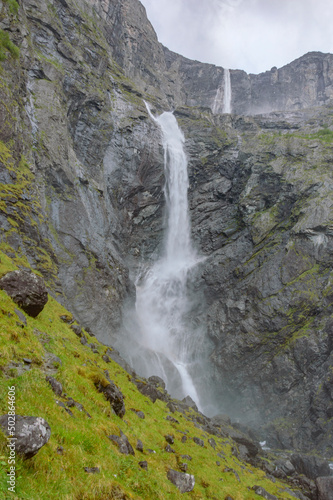 Mardalsfossen waterfall in Norway. White water stream  grey rocky mountains  green grass  clouds of the water dust