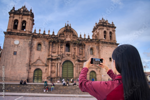 Turista de espaldas tomando una foto de la catedral de Cuzco