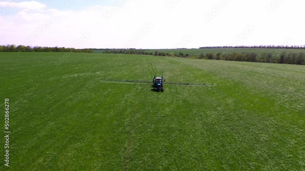 Aerial view of farming tractor spraying on field with sprayer, herbicides and pesticides at sunset. Farm machinery spraying insecticide to the green field, agricultural natural seasonal spring works. Aerial view of farming tractor spraying on field with sprayer, herbicides and pesticides at sunset. Farm machinery spraying insecticide to the green field, agricultural natural seasonal spring works.