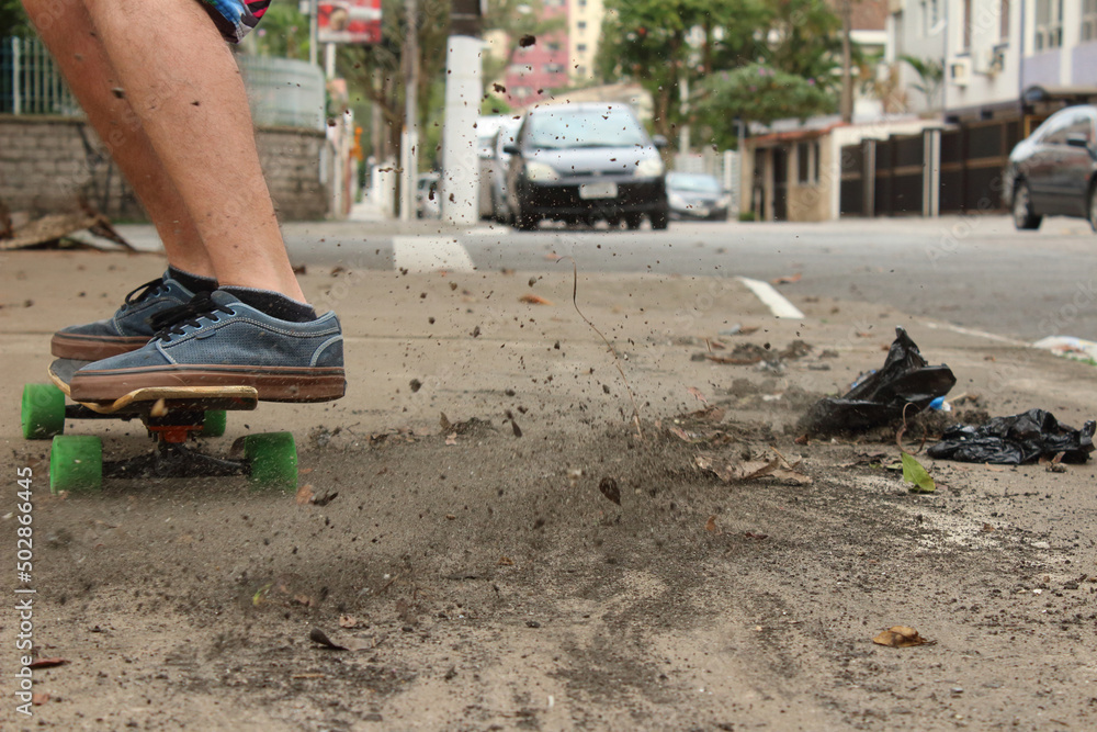 Skater on the sidewalk kicking up dust, green wheels Skater on the sidewalk kicking up dust, green wheels