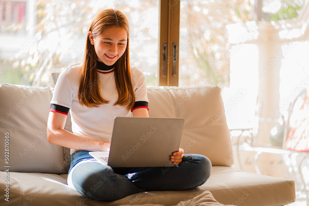 Asian woman sitting on sofa working online with laptop work at home concept Asian woman sitting on sofa working online with laptop work at home concept