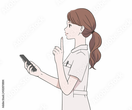 スマートフォンを持ち、人差し指を立てる看護師