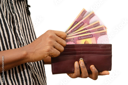 fair Female Hand Holding brown Purse With Afghan afghani notes, hand removing money out of purse isolated on white. removing money from wallet photo