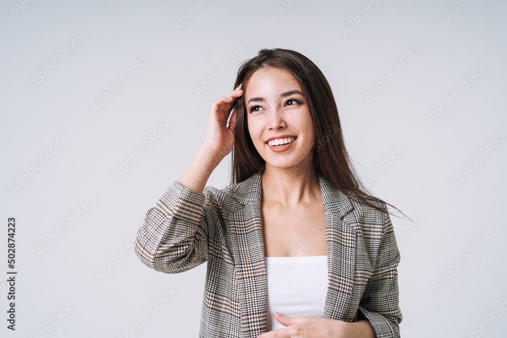 Young happy asian woman with long hair in suit on grey background Young happy asian woman with long hair in suit on grey background