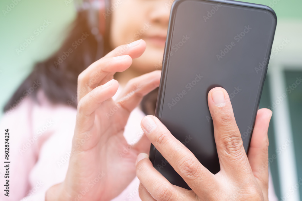 Happy woman holding mobile with blur wearing Headphones.portrait Lady finger touch screen smartphone and smile.she Video call to friend.Technology internet communication for lifestyles concept.
