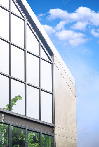 Geometric pattern of steel and glass wall on office building in loft style against blue sky background in vertical frame