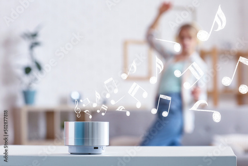 Wireless portable speaker in room and dancing woman on background photo