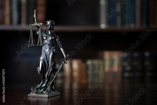 Judge office. Themis statue on the judge desk. Book shelf in the background.