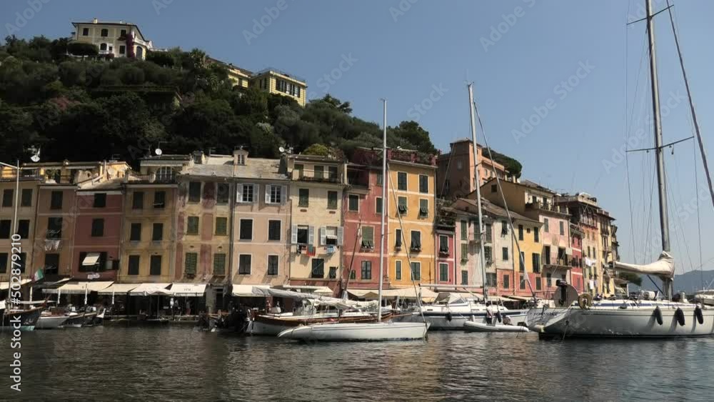 Semi close shot of quiet fishing village Portofino, Italy facing houses in the summer with small boats in de harbour Semi close shot of quiet fishing village Portofino, Italy facing houses in the summer with small boats in de harbour