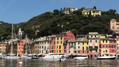 Shot of quiet fishing village Portofino, Italy facing houses and mountain with small boats in de harbour photo