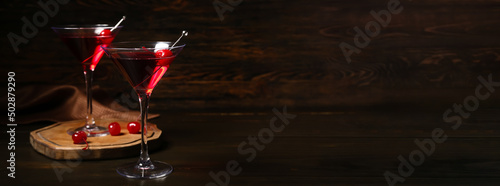 Glasses of delicious Manhattan cocktail on dark background with space for text photo