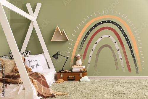 Interior of modern children's room with painted rainbow on wall