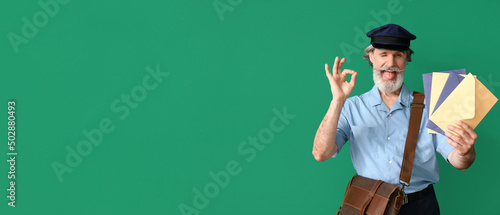 Foto Handsome old postman showing OK on green background with space for text