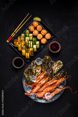 A sushi set  oysters and langoustines  soy sauce  view from above on black background