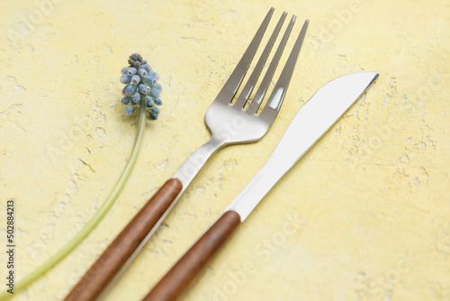 Silver fork  knife and Muscari flower on yellow background  closeup