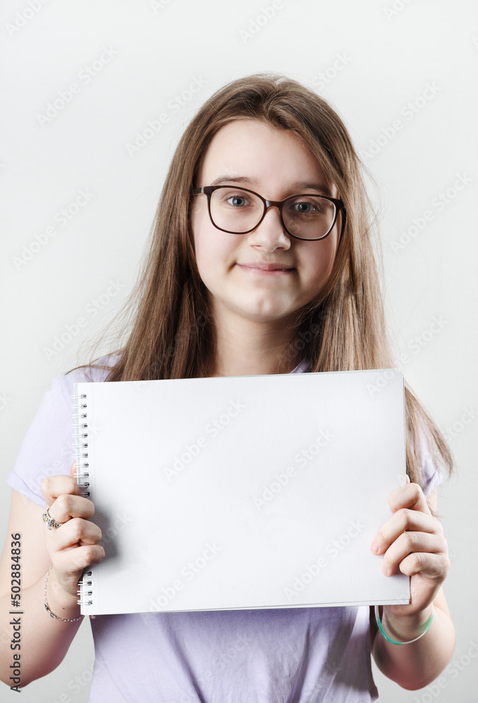 Teen girl wearing glasses showing blank sketchbook. Education concept. Teen girl wearing glasses showing blank sketchbook. Education concept.