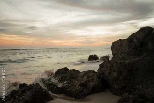 Beautiful sunset at seashore with rocks and sand