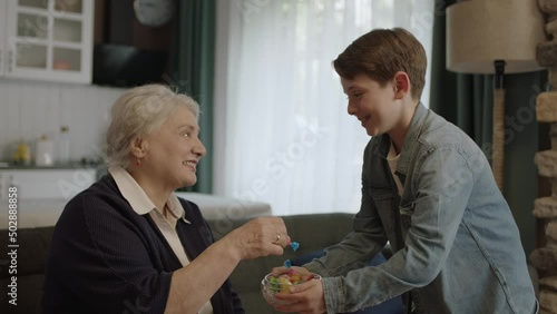 Boy offering candy in bowl to his elderly grandmother.Little boy offering candy to his elderly grandmother to celebrate the traditional Eid al-Fitr (candy feast) after the end of Ramadan.