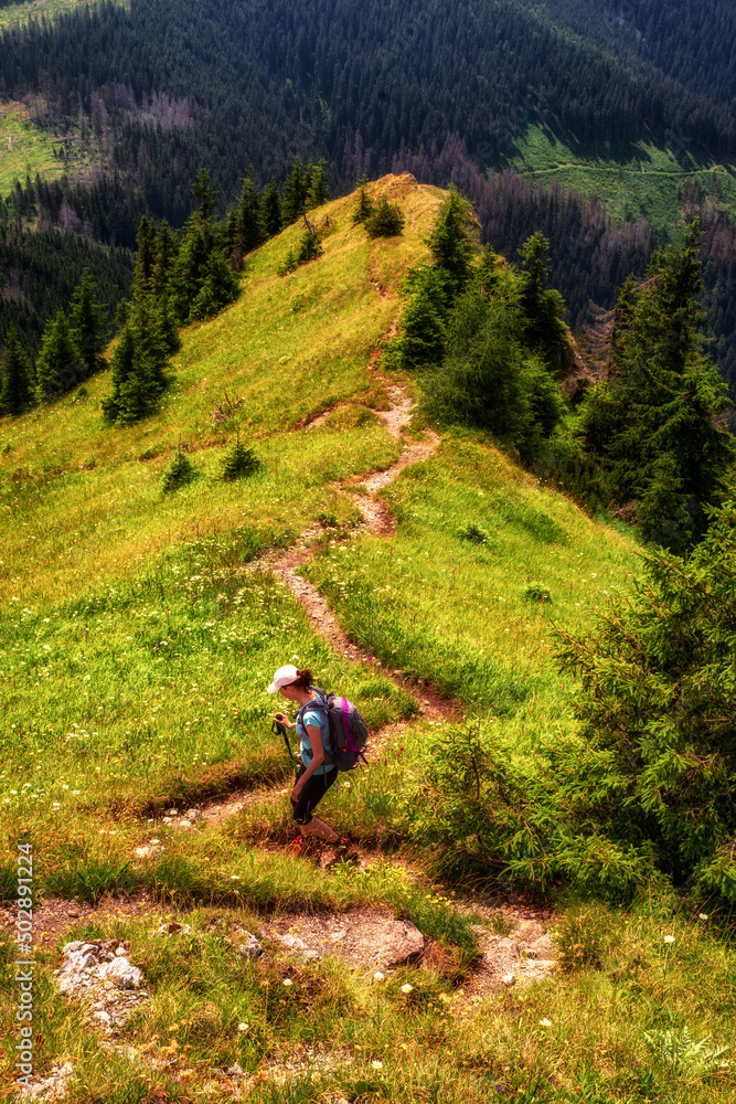 Tourist woman on hiking trail in hillside of mountains