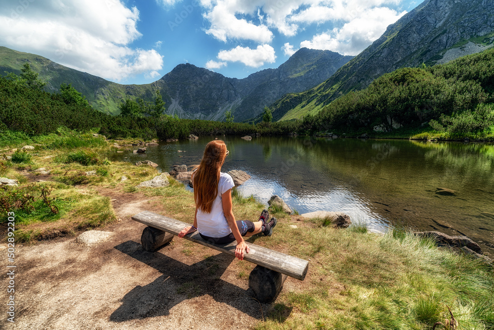 Girl sitting and looking on beautiful nature with lake and mountains in Western Tatras in Slovakia