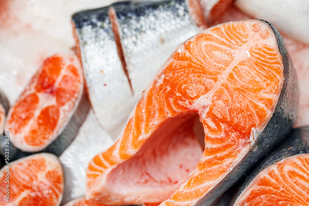 Trout, cut into pieces, laid out on ice on store counter. Pieces of red fish in close-up. Trout, cut into pieces, laid out on ice on store counter. Pieces of red fish in close-up.
