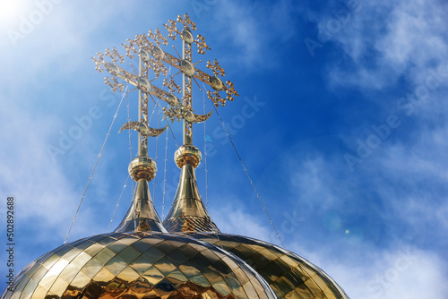 Oriental Orthodox crosses on golden domes of temple against blue sky with clouds. Trinity Cathedral of Raifa Monastery, Tatarstan, Russia.