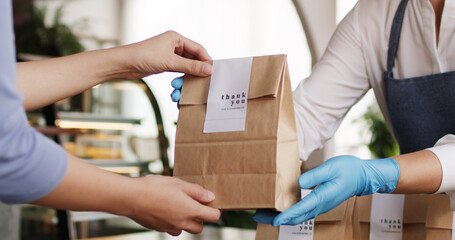 Asia people woman hand glove or face mask happy enjoy buy fast food carry send paper box pick up take home to-go lunch meal. Small cafe coffee shop work with wrap care new normal for SME omni channel.