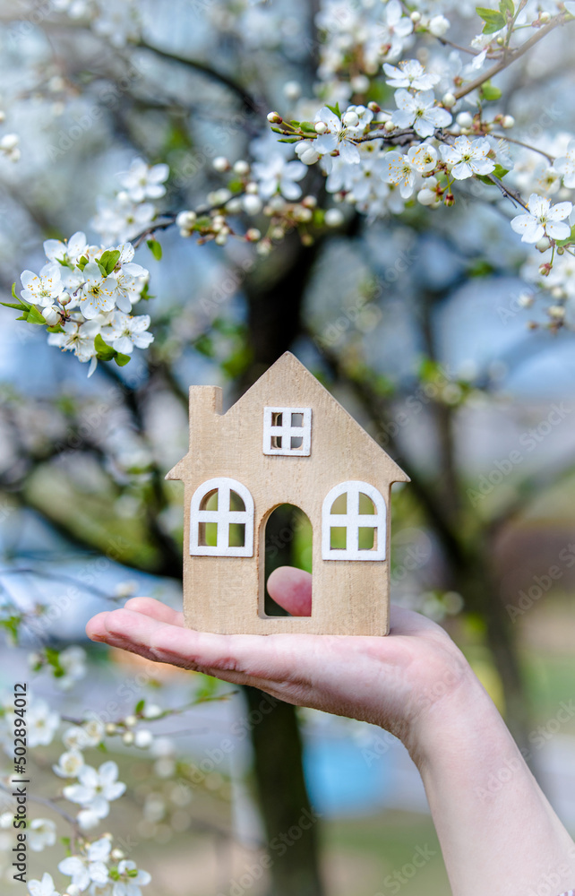 The girl holds the house symbol against the background of blossoming cherry
The girl holds the house symbol against the background of blossoming cherry