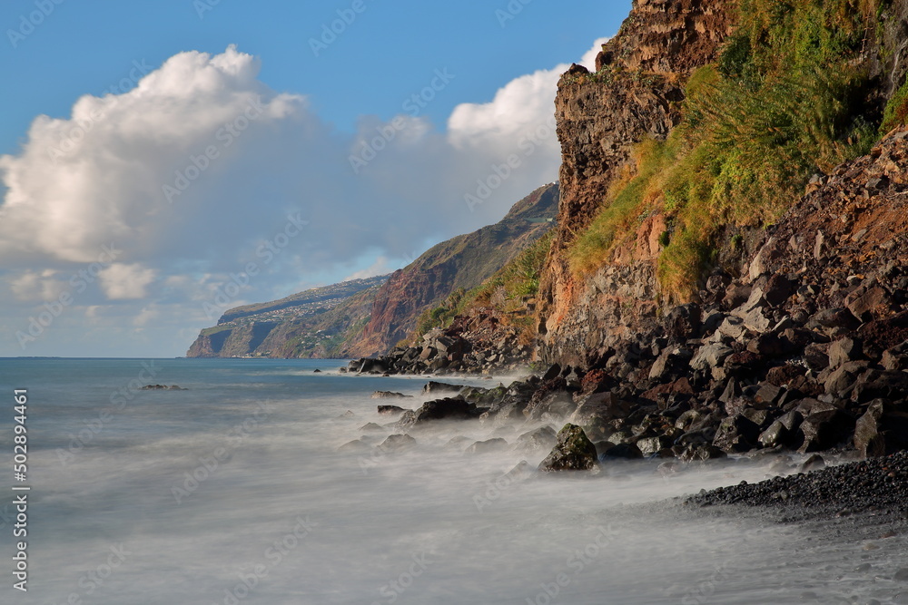 The South coast of Madeira Island, Portugal, viewed from the beach of Ponta de Sol towards the West, with rocky cliffs