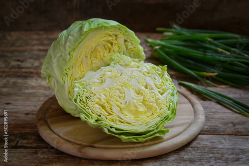 Young white cabbage cut on a wooden board.