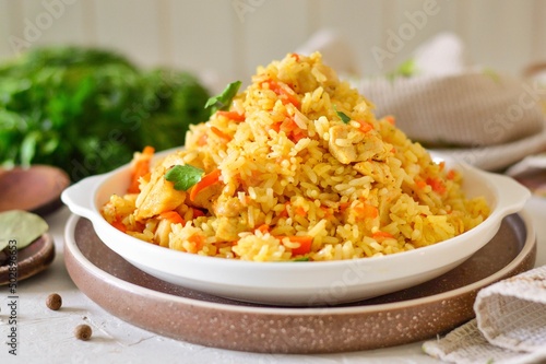 Appetizing pilaf in a white plate on a light background. Rice with vegetables and meat.