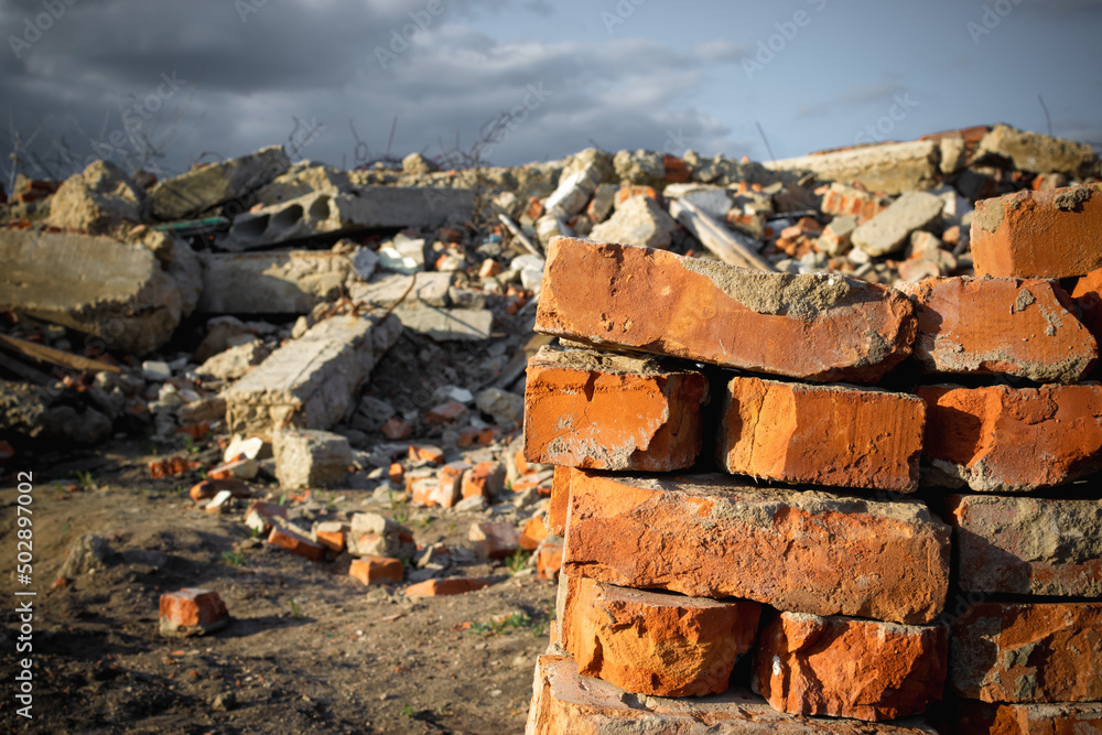 Fototapeta premium Red bricks on the background of a destroyed building and blue sky