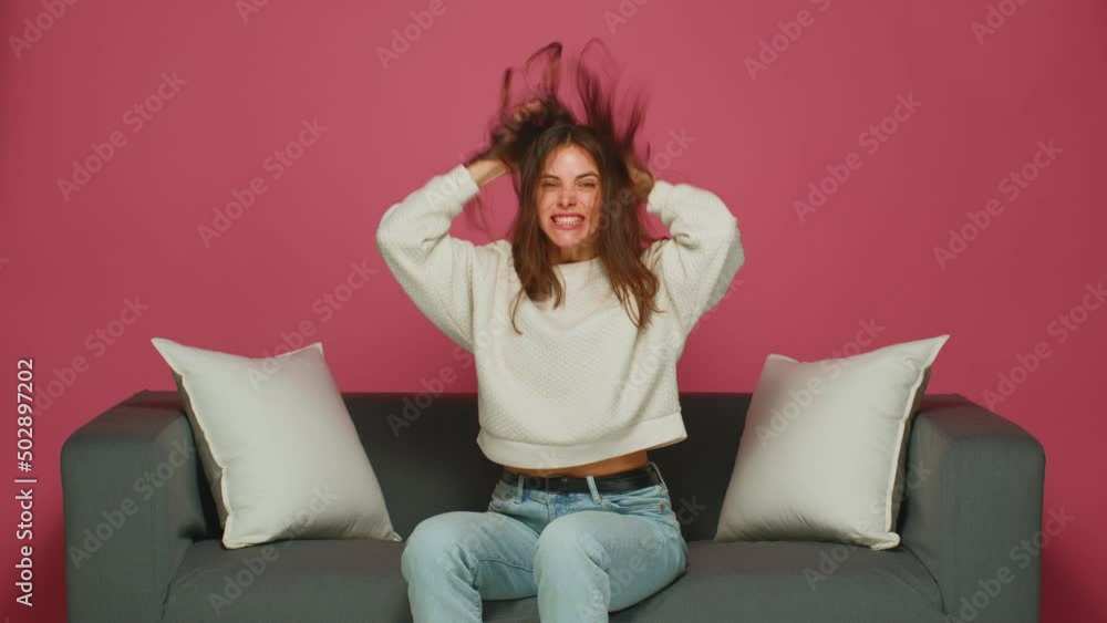 Joyful energetic excited young girl ruffle long hair, shaking head, enjoy healthy hairs, having fun sitting on sofa Joyful energetic excited young girl ruffle long hair, shaking head, enjoy healthy hairs, having fun sitting on sofa