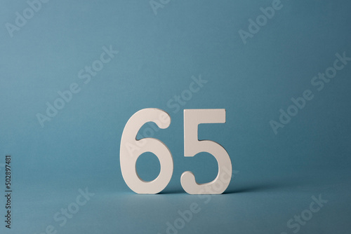 White wooden number sixty-five 65 on blue background.
