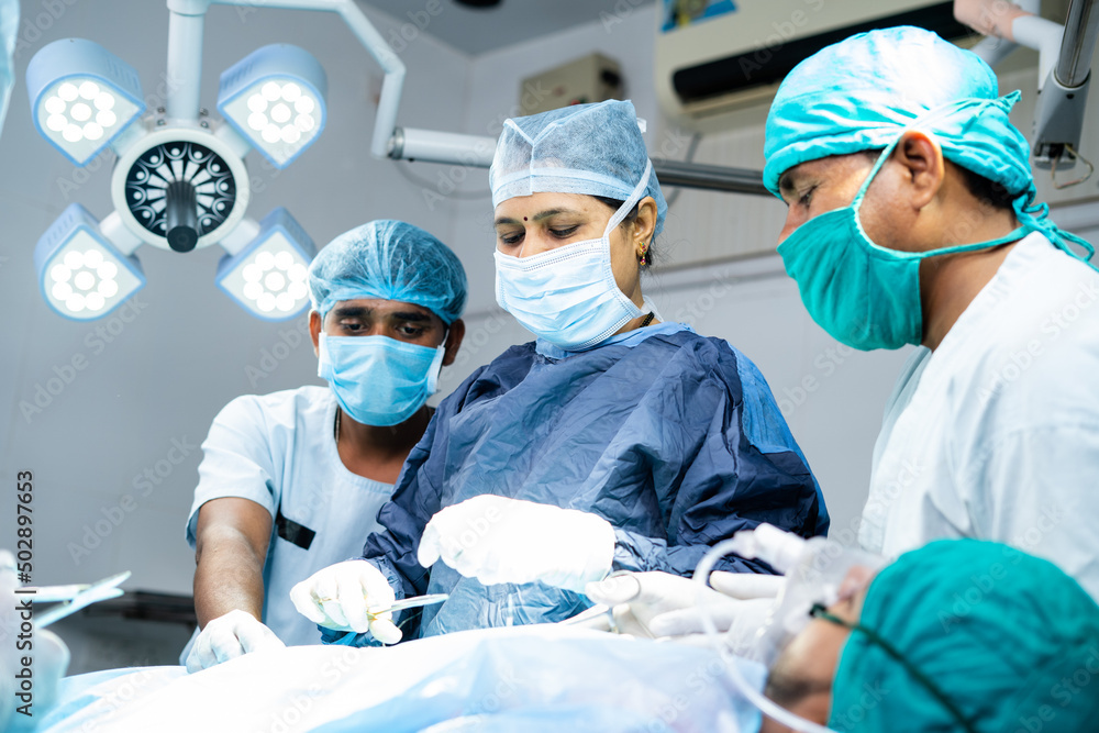 Woman surgeon with supporting practitioners busy doing surgery at ...