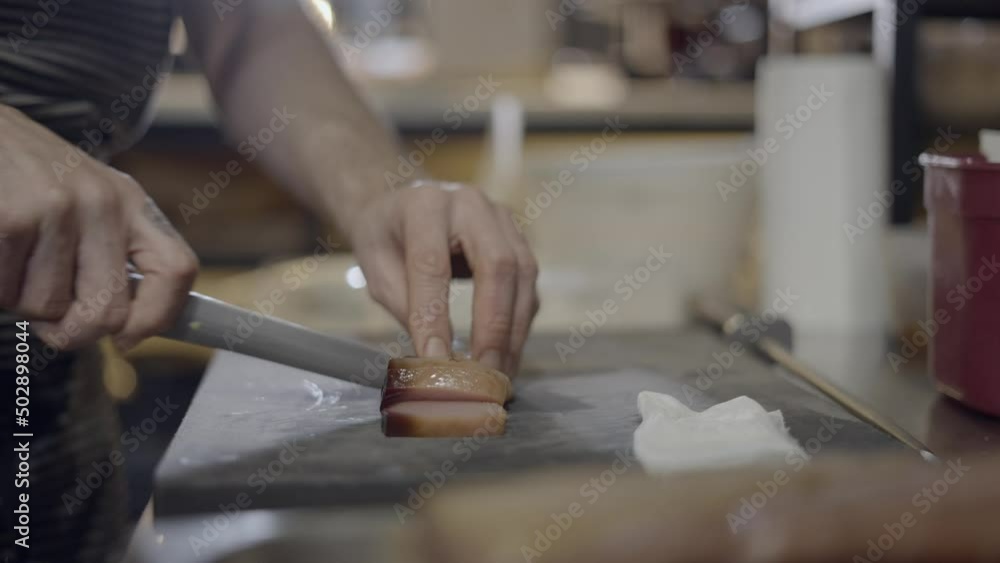 Close side view of chef slicing food with sharp knife, no face Close side view of chef slicing food with sharp knife, no face