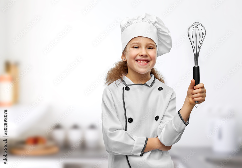 cooking, culinary and profession concept - happy smiling little girl in chef's toque and jacket with whisk over kitchen background cooking, culinary and profession concept - happy smiling little girl in chef's toque and jacket with whisk over kitchen background
