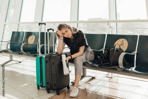 Cuadro en lienzo Bored blond woman with luggage, leaning elbow on bags, sit in waiting room at ai