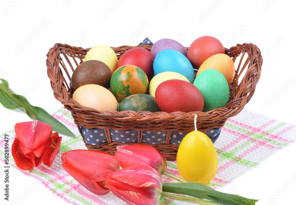Close up of colorful Easter eggs in a basket and colorful tulip decorations on an isolated white background Close up of colorful Easter eggs in a basket and colorful tulip decorations on an isolated white background