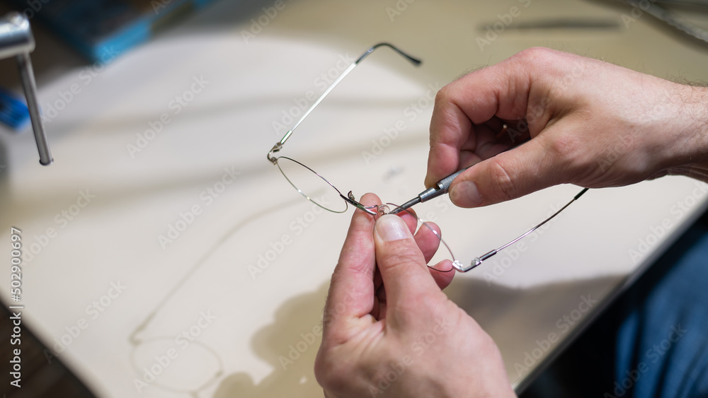 Installation of nose pads in glasses. A male technician repairs broken glasses Installation of nose pads in glasses. A male technician repairs broken glasses