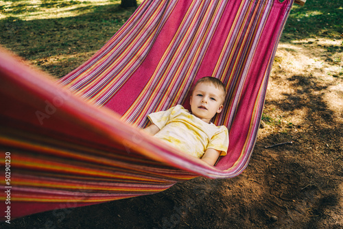Little boy lies in a colored hammock.