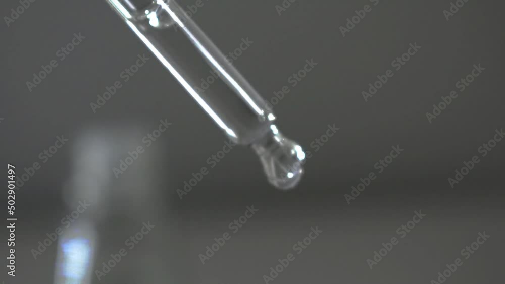 Glass transparent pipette dropper for medical, cosmetic, scientific biology and chemistry laboratory procedures being used by industry professional by dripping liquid water solution droplet Glass transparent pipette dropper for medical, cosmetic, scientific biology and chemistry laboratory procedures being used by industry professional by dripping liquid water solution droplet