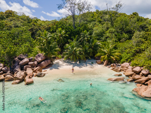 Praslin Seychelles tropical island with withe beaches and palm trees, couple of men and women mid age on vacation at Seychelles visiting the tropical beach Anse Lazio Praslin Seychelles. drone view 