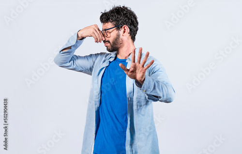 Confused unhappy man grabbing nose with fingers and stretching hand out feeling disgusted, A man with covering his nose