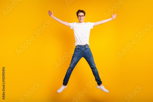 Full length photo of young guy good mood jump up wear casual clothes isolated over yellow color background