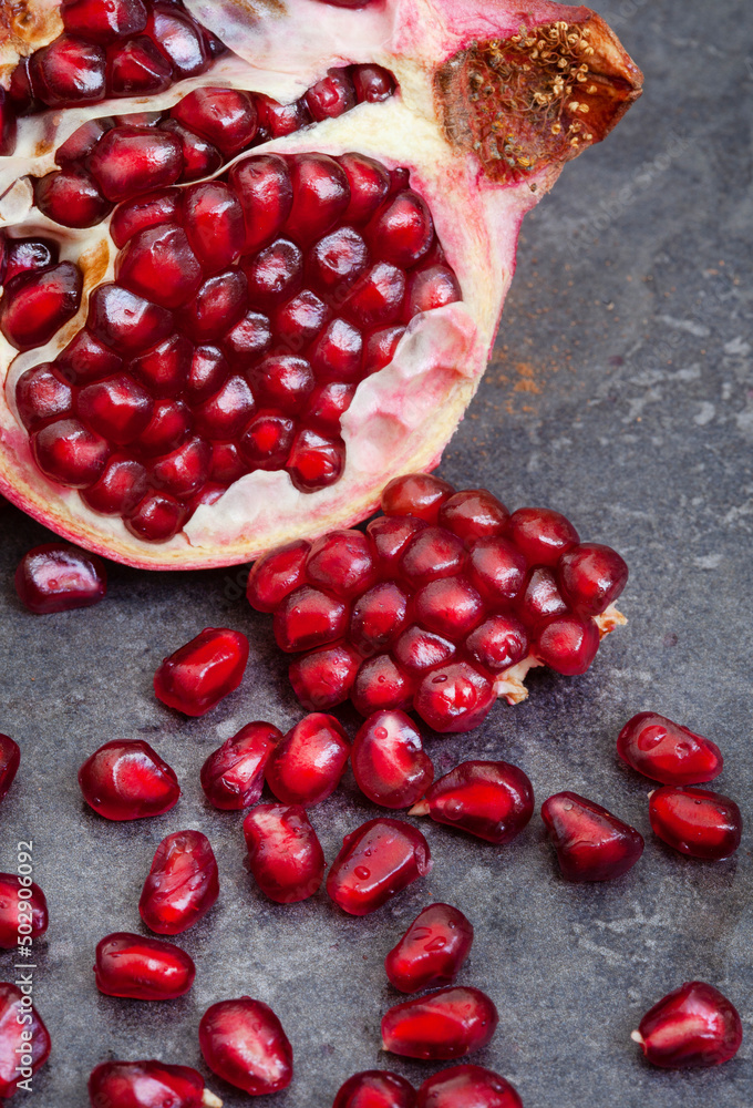 Pomegranate broken open with pips on a grunge surface with copy space Pomegranate broken open with pips on a grunge surface with copy space
