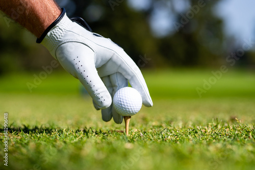 Golfer hitting golf shot with club on course. Hand with golf glove.